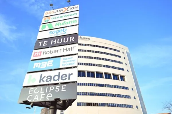 Bedrijvensigning met namen van huurders voor het kantoorgebouw Rivium Quadrant tegen een heldere blauwe lucht.